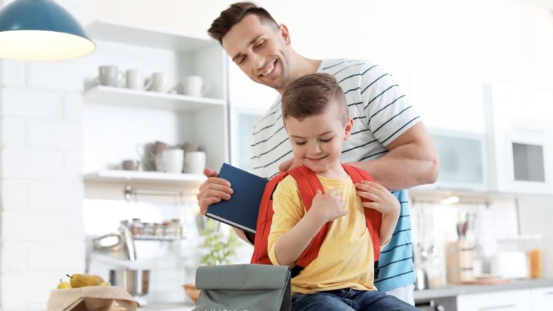 dad helping books in backpack for child going back to school