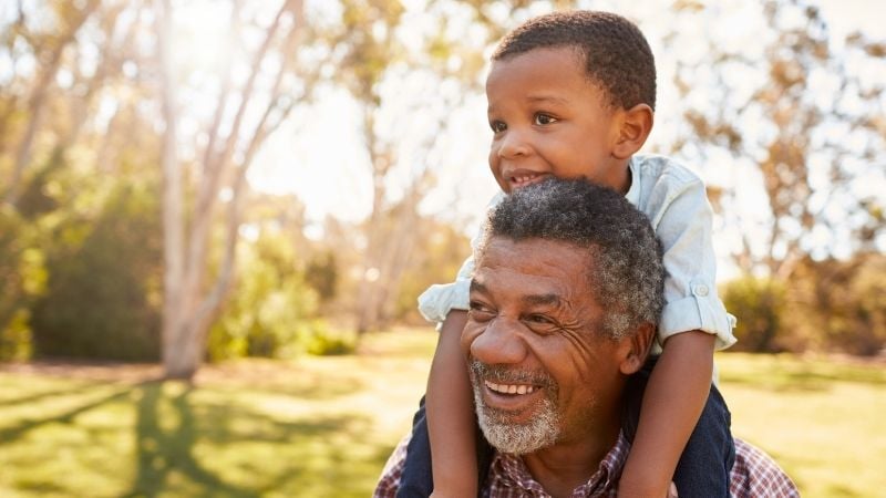 A grandfather carrying his grandson on his shoulders