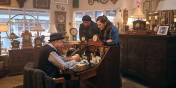hannah and franklin with watch maker in clock shop